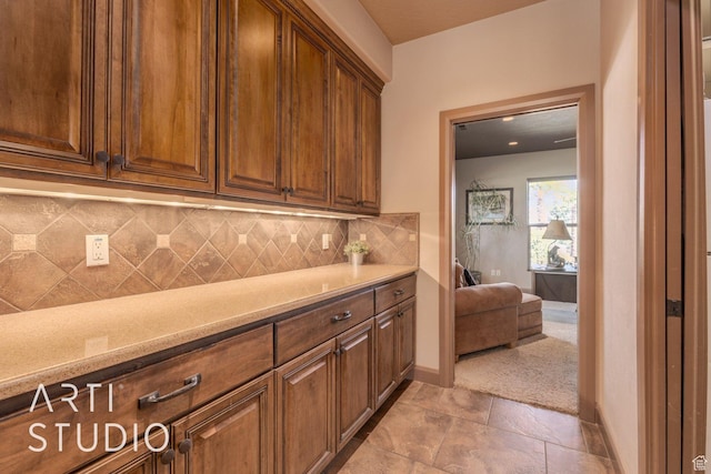 1285 Summerwood Cir, Santa Clara, UT 84765 - kitchen with brown cabinetry, baseboards, backsplash, and light stone countertops