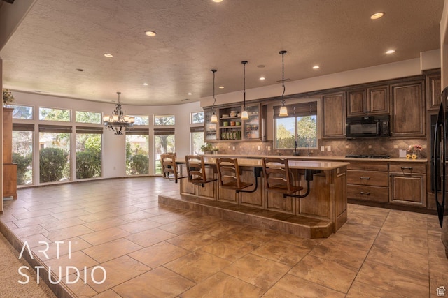 1285 Summerwood Cir, Santa Clara, UT 84765 - kitchen with light countertops, gas stovetop, black microwave, decorative backsplash, and a breakfast bar area