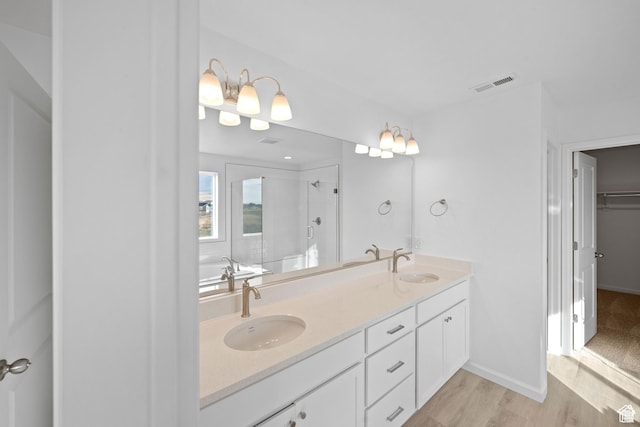full bath with a sink, visible vents, a shower stall, and double vanity