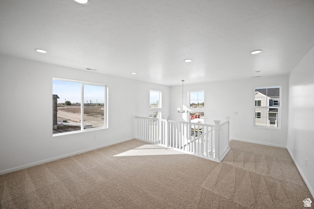 spare room featuring carpet floors, baseboards, recessed lighting, and plenty of natural light