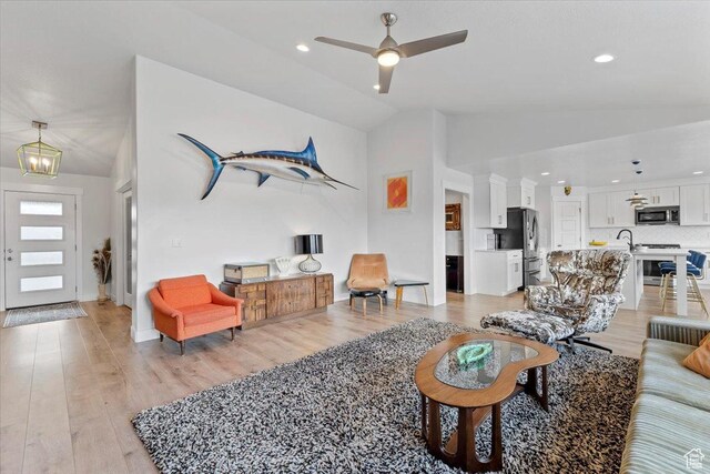 living area featuring recessed lighting, light wood-style flooring, ceiling fan with notable chandelier, and vaulted ceiling