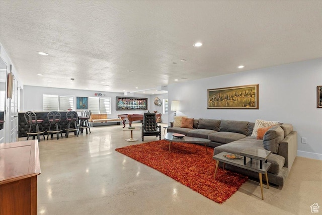 living room featuring baseboards, recessed lighting, finished concrete floors, and a textured ceiling