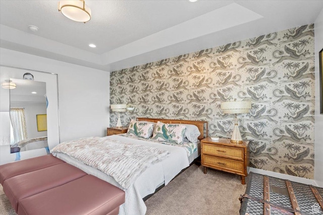 bedroom featuring a raised ceiling, wallpapered walls, baseboards, and carpet