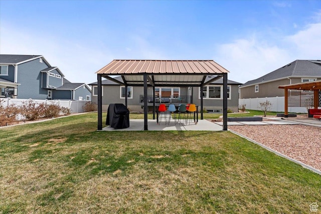 rear view of house featuring a lawn, a patio, metal roof, fence, and a gazebo