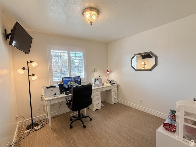 office area featuring light wood-style floors, baseboards, and a textured ceiling
