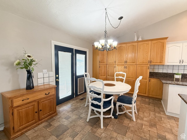 dining room featuring lofted ceiling, an inviting chandelier, and stone finish flooring