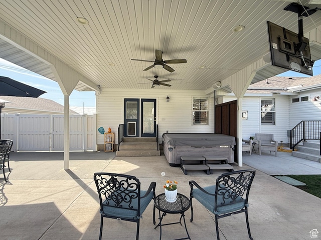 view of patio with entry steps, ceiling fan, fence, and a hot tub