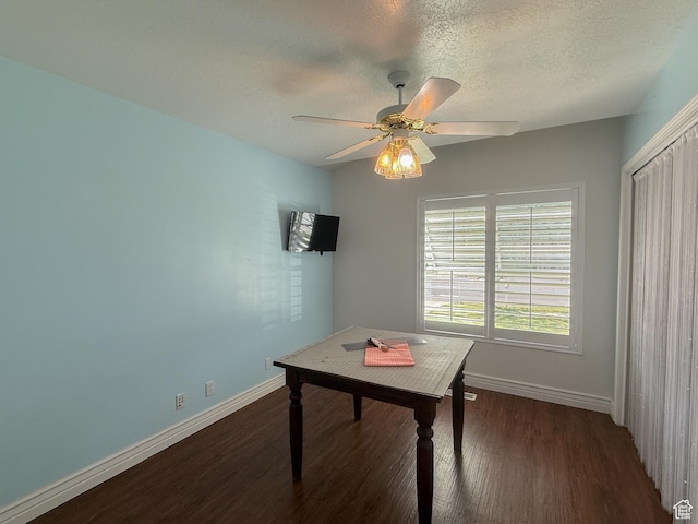 office area featuring dark wood-type flooring, a textured ceiling, ceiling fan, and baseboards
