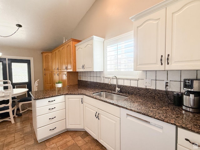 kitchen featuring dark stone countertops, a sink, backsplash, and a wealth of natural light