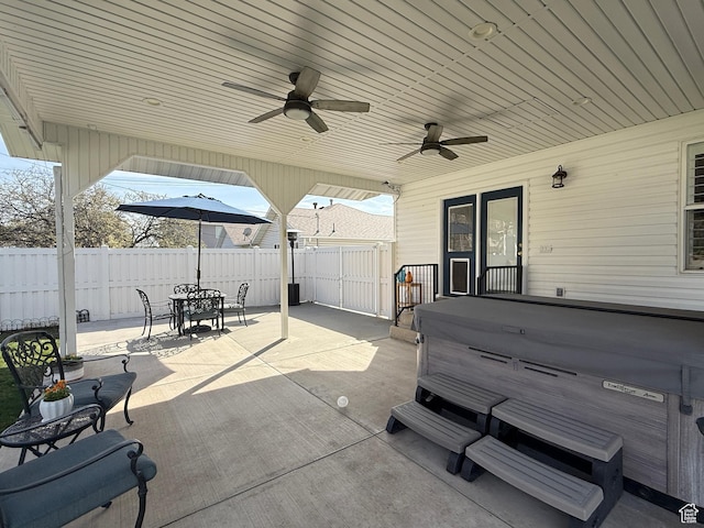 view of patio / terrace featuring ceiling fan, fence, outdoor dining space, and a hot tub