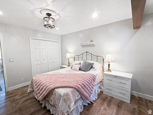 bedroom featuring dark wood-style flooring, a closet, and baseboards