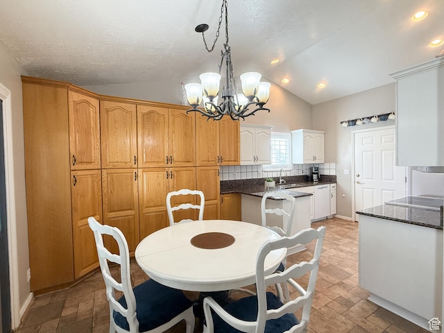 dining room featuring a textured ceiling, stone finish flooring, recessed lighting, a chandelier, and lofted ceiling