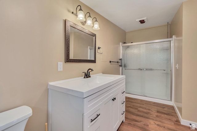 bathroom with toilet, wood finished floors, vanity, and a shower stall