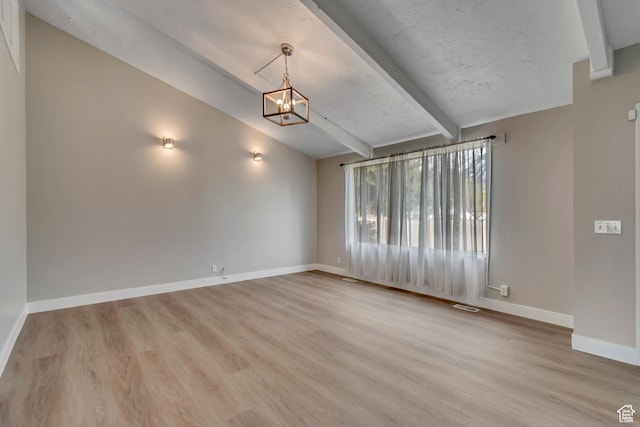 empty room with baseboards, an inviting chandelier, a textured ceiling, vaulted ceiling with beams, and wood finished floors