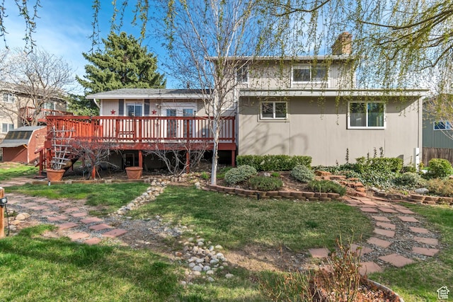 rear view of property with a chimney, a deck, and a lawn