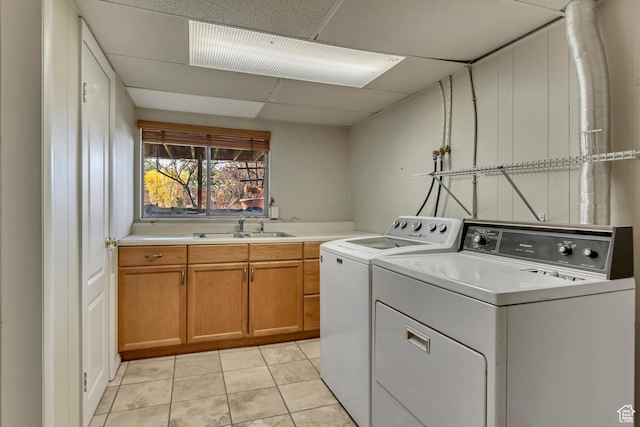 laundry area with a sink, light tile patterned floors, washer and clothes dryer, and cabinet space