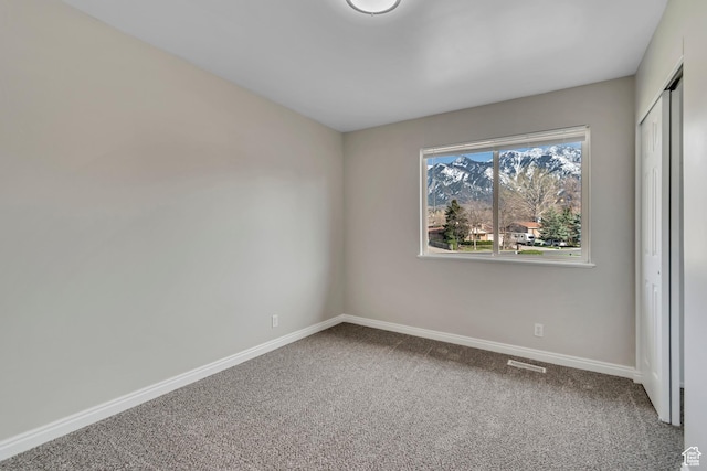 unfurnished room with carpet flooring, visible vents, and baseboards