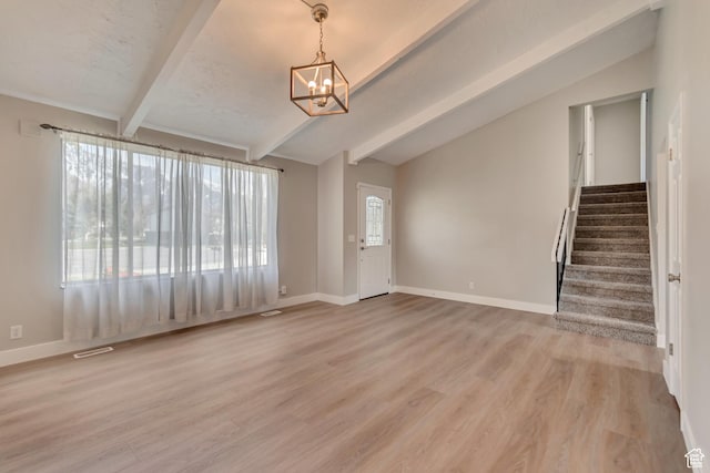 unfurnished living room featuring light wood-type flooring, a chandelier, lofted ceiling with beams, and stairs