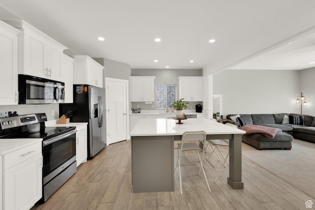 3632 E Sapphire Creek Ln N Unit 318, Eagle Mountain, UT 84005 - kitchen featuring stainless steel appliances, a center island, open floor plan, white cabinetry, and light countertops