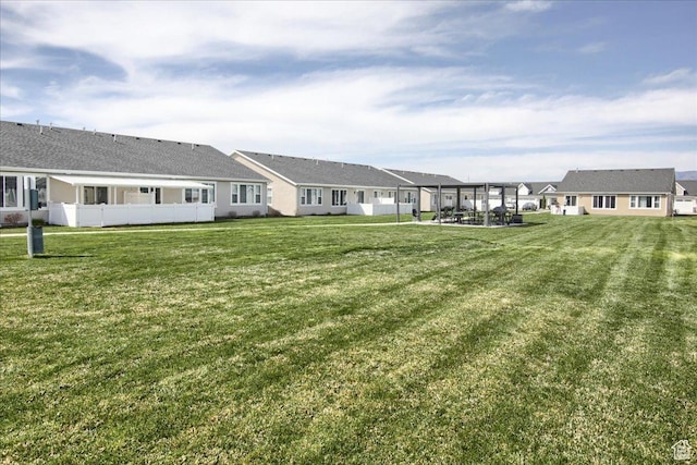 rear view of house featuring a residential view, fence, and a lawn