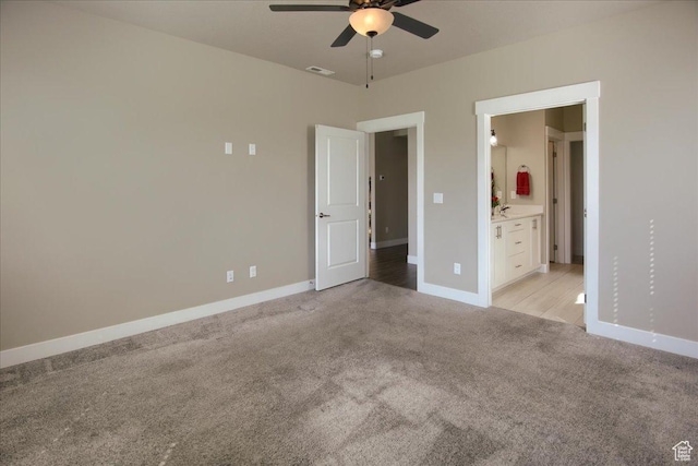 unfurnished bedroom featuring baseboards, light carpet, ensuite bath, visible vents, and ceiling fan