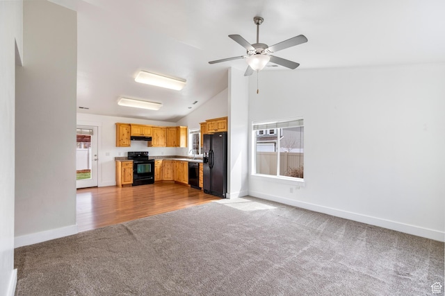 kitchen featuring a healthy amount of sunlight, under cabinet range hood, black appliances, and carpet floors