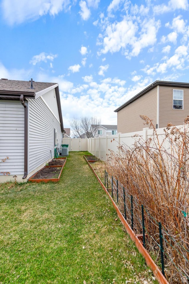 view of yard featuring a garden, a fenced backyard, and central air condition unit