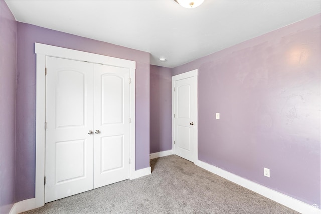 unfurnished bedroom featuring light carpet, a closet, and baseboards