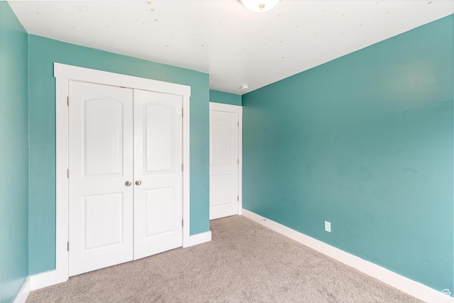 unfurnished bedroom with a closet, baseboards, and carpet