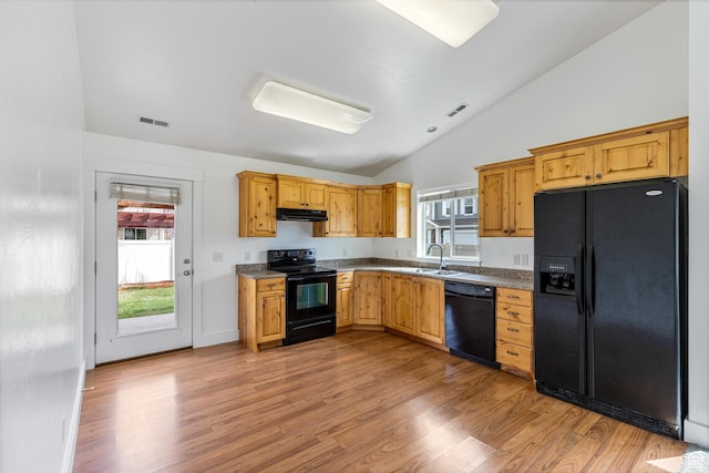 kitchen with visible vents, light wood-type flooring, under cabinet range hood, black appliances, and lofted ceiling