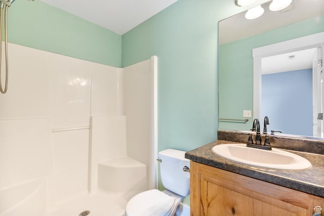 bathroom featuring toilet, a shower, and vanity