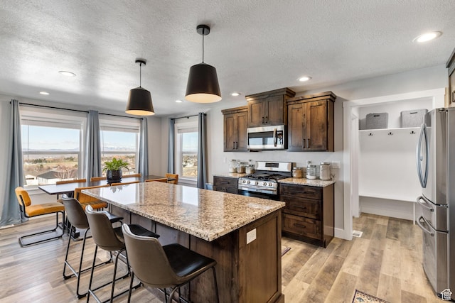 51 S 1250 E, Smithfield, UT 84335 - kitchen featuring a center island, decorative light fixtures, light wood-type flooring, light stone countertops, and stainless steel appliances