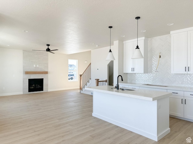 7007 W Hazel Oak Ct Unit 212, Herriman, UT 84096 - kitchen with a ceiling fan, a center island with sink, light wood-type flooring, tasteful backsplash, and light countertops