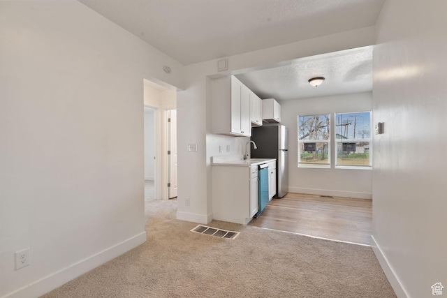 924 W California Ave, Salt Lake City, UT 84104 - kitchen with light countertops, white cabinetry, visible vents, dishwasher, and light colored carpet