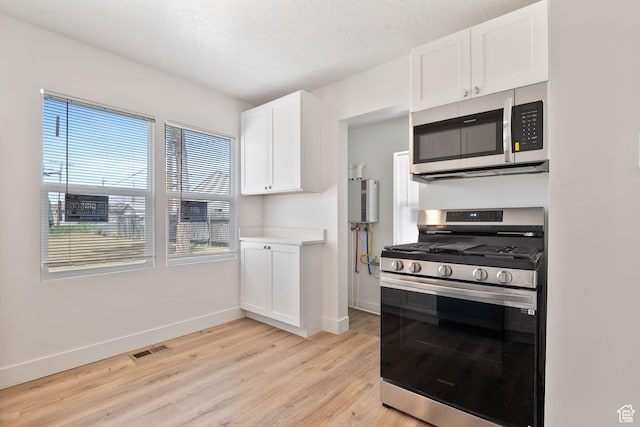 924 W California Ave, Salt Lake City, UT 84104 - kitchen featuring visible vents, white cabinets, baseboards, light wood-style floors, and stainless steel appliances
