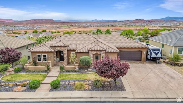view of front of home featuring a mountain view, an attached garage, driveway, and stucco siding