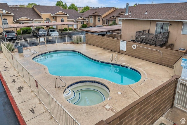 community pool with a patio, fence, a residential view, and a hot tub