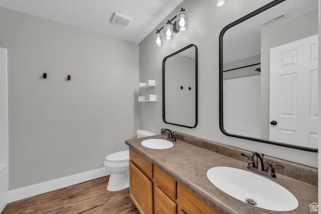 bathroom featuring visible vents, a sink, toilet, and wood finished floors