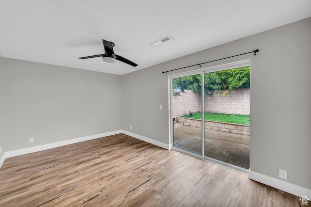 empty room with visible vents, ceiling fan, baseboards, and wood finished floors