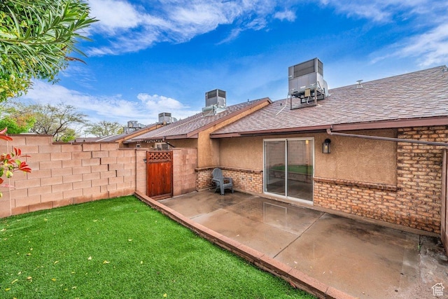 rear view of house featuring a patio area, a lawn, fence, stucco siding, and roof with shingles
