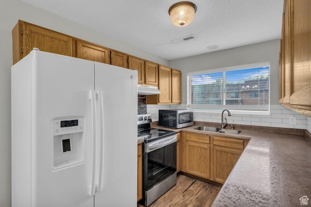 kitchen featuring visible vents, a sink, appliances with stainless steel finishes, under cabinet range hood, and backsplash