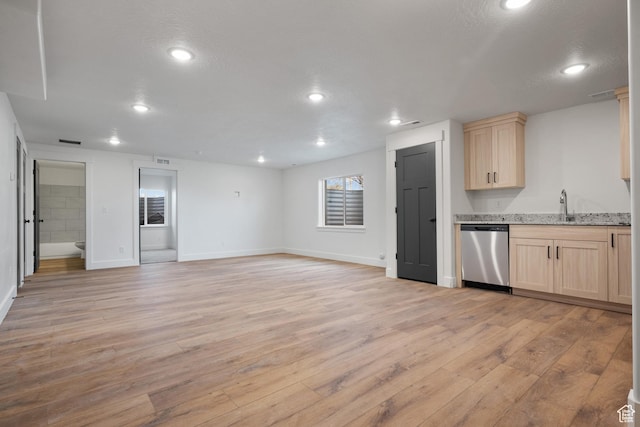 kitchen with light wood-style flooring, dishwasher, a sink, open floor plan, and light brown cabinets