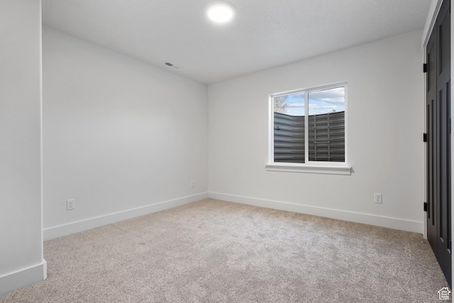 carpeted spare room featuring baseboards and visible vents