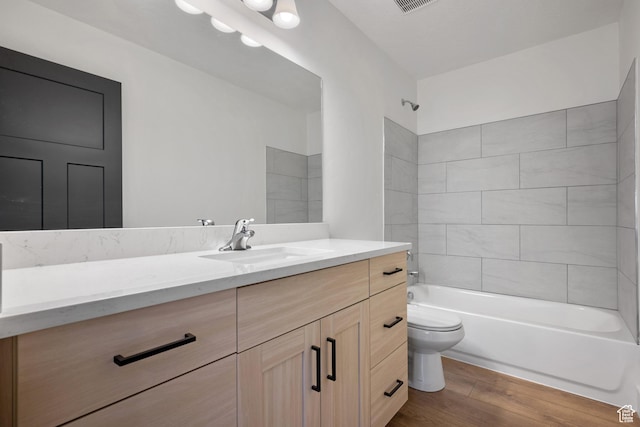 full bathroom with visible vents, shower / washtub combination, toilet, vanity, and wood finished floors