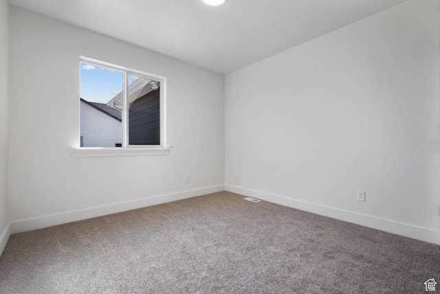 empty room featuring visible vents, baseboards, and carpet