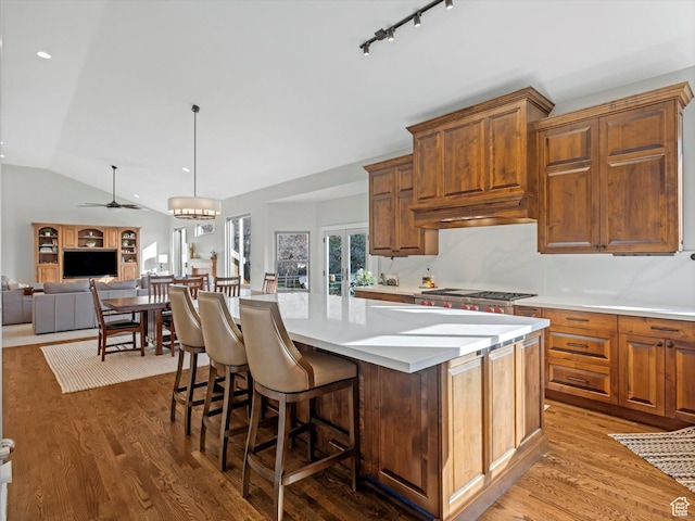 kitchen with light wood-style floors, a center island, light countertops, a ceiling fan, and vaulted ceiling