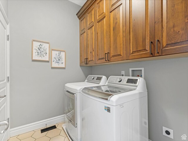 clothes washing area with baseboards, cabinet space, separate washer and dryer, and visible vents