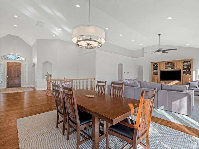 dining area with arched walkways, ceiling fan with notable chandelier, recessed lighting, and wood finished floors