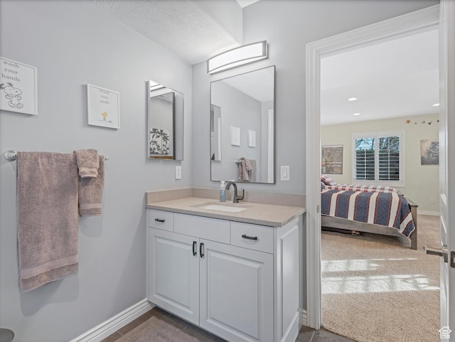 bathroom with vanity, baseboards, and ensuite bath