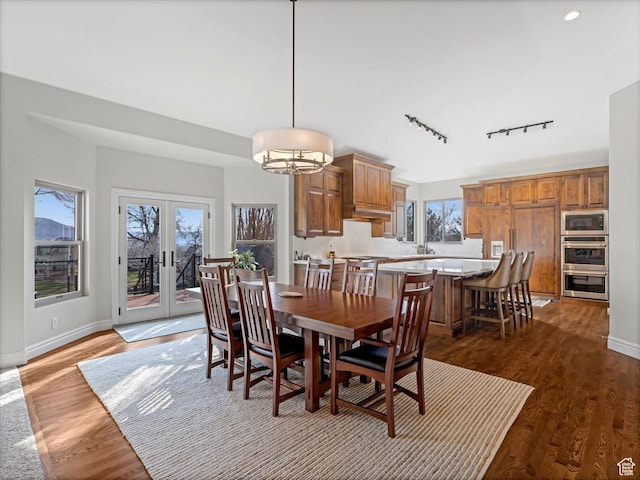 dining area with track lighting, dark wood-style flooring, baseboards, and french doors